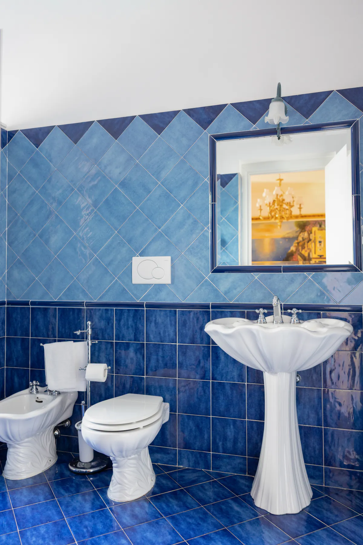 Un bagno della villa rivestito di maiolica blu, con il lavabo a colonna