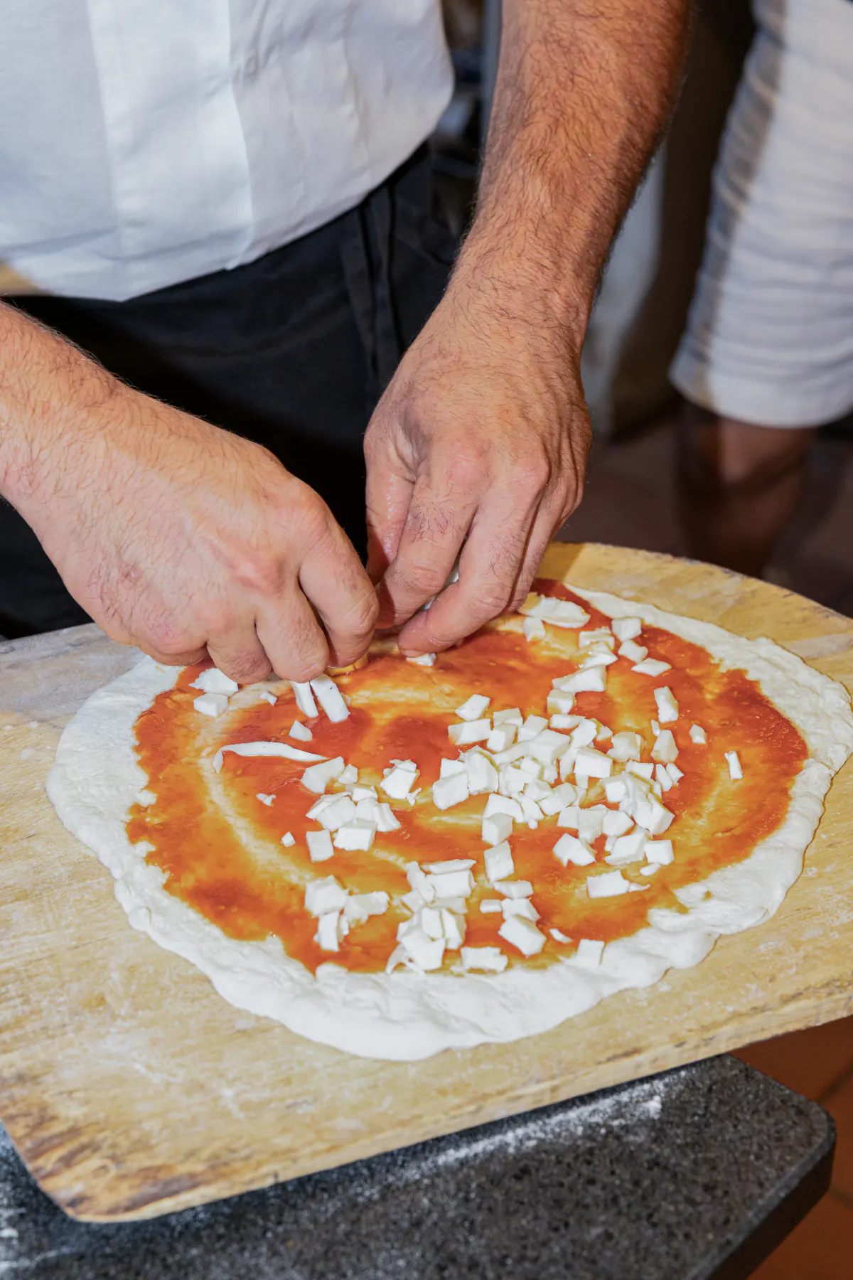 Il fiordilatte disposto a mano sulla pizza prima di infornarla