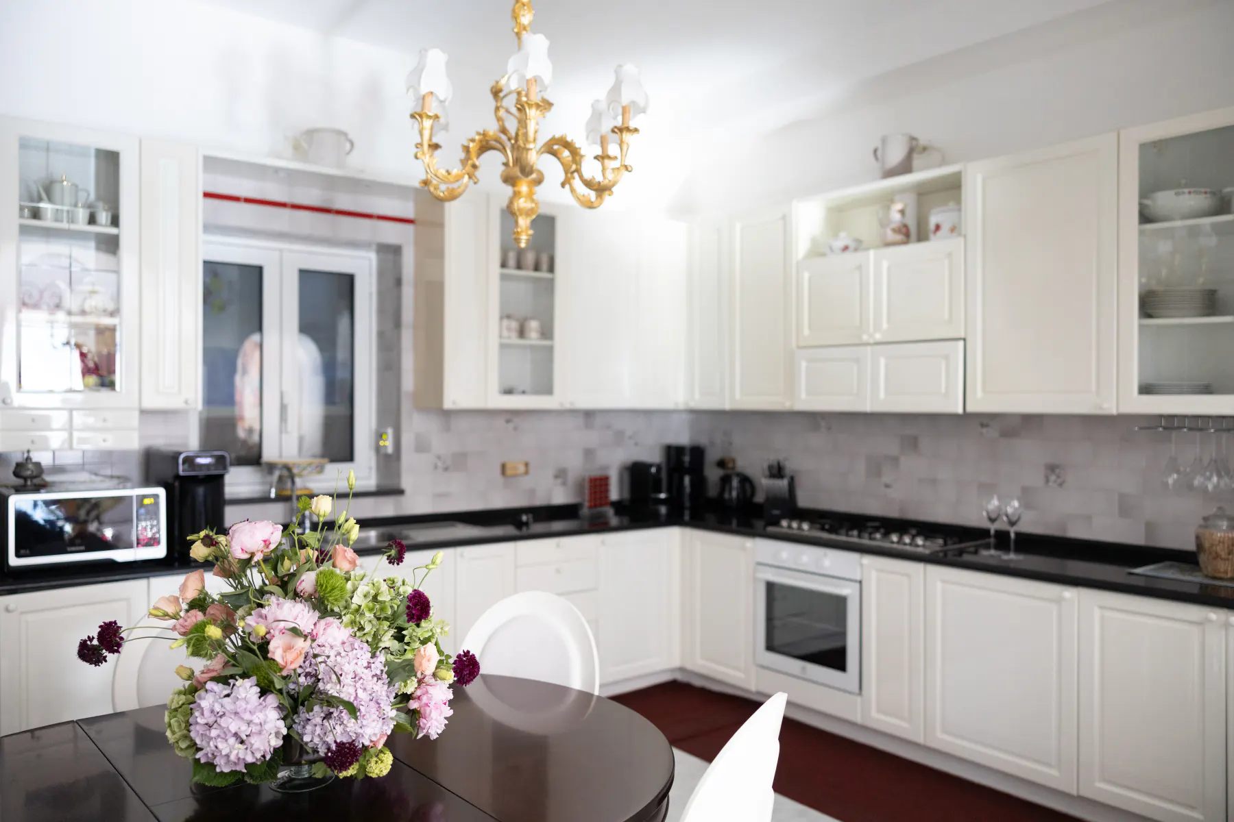 La cucina bianca della villa con un mazzo di fiori sul tavolo