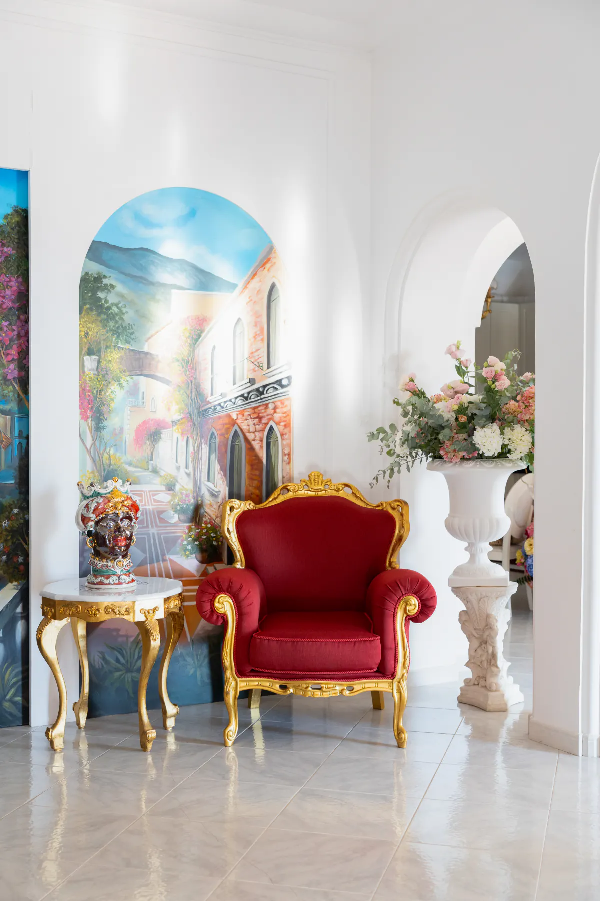 Una sala della villa con Positano dipinta a parete e la poltrona dorata