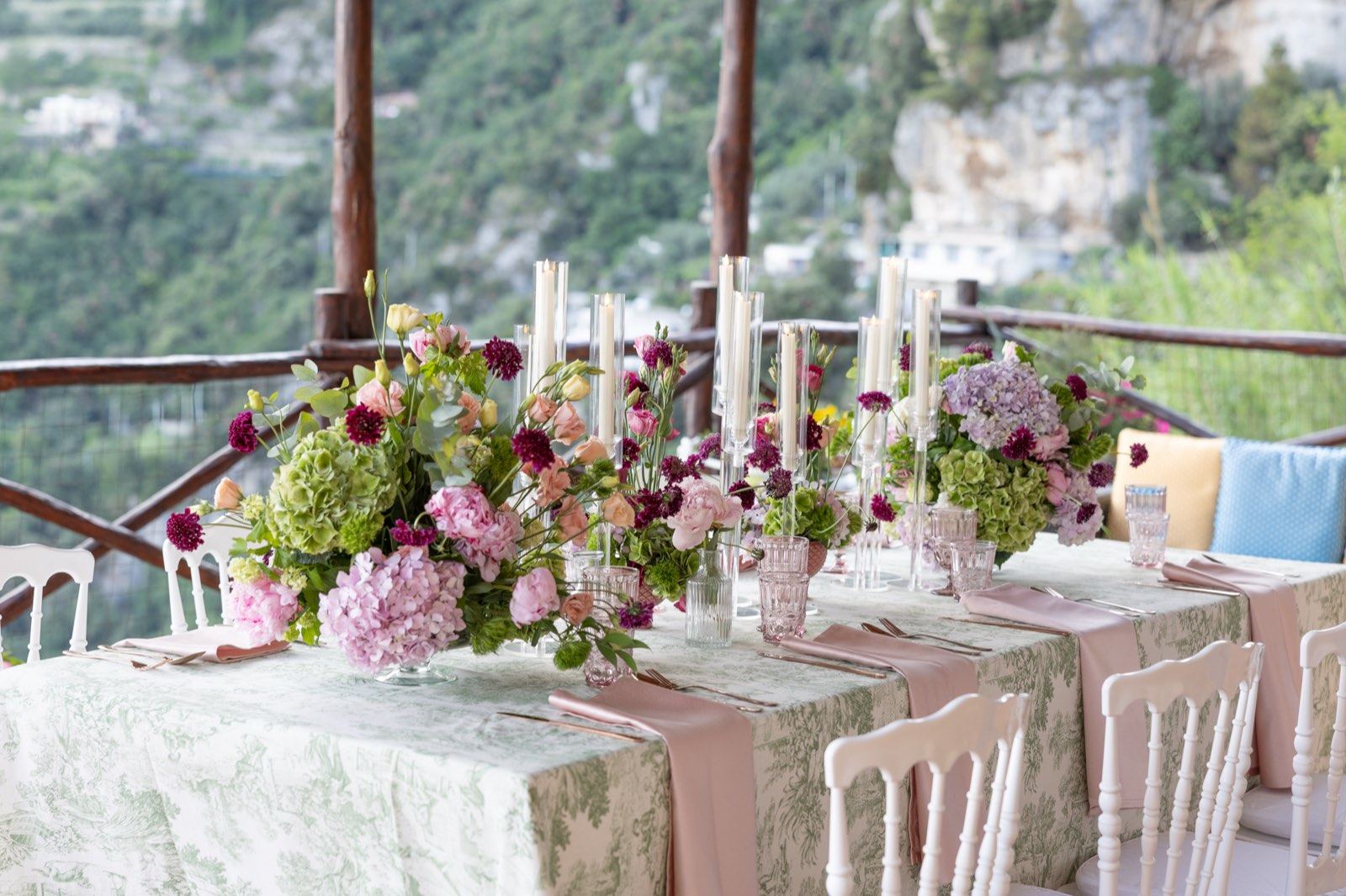 La tavola lunga del ricevimento con i fiori, sotto il pergolato affacciato su Positano