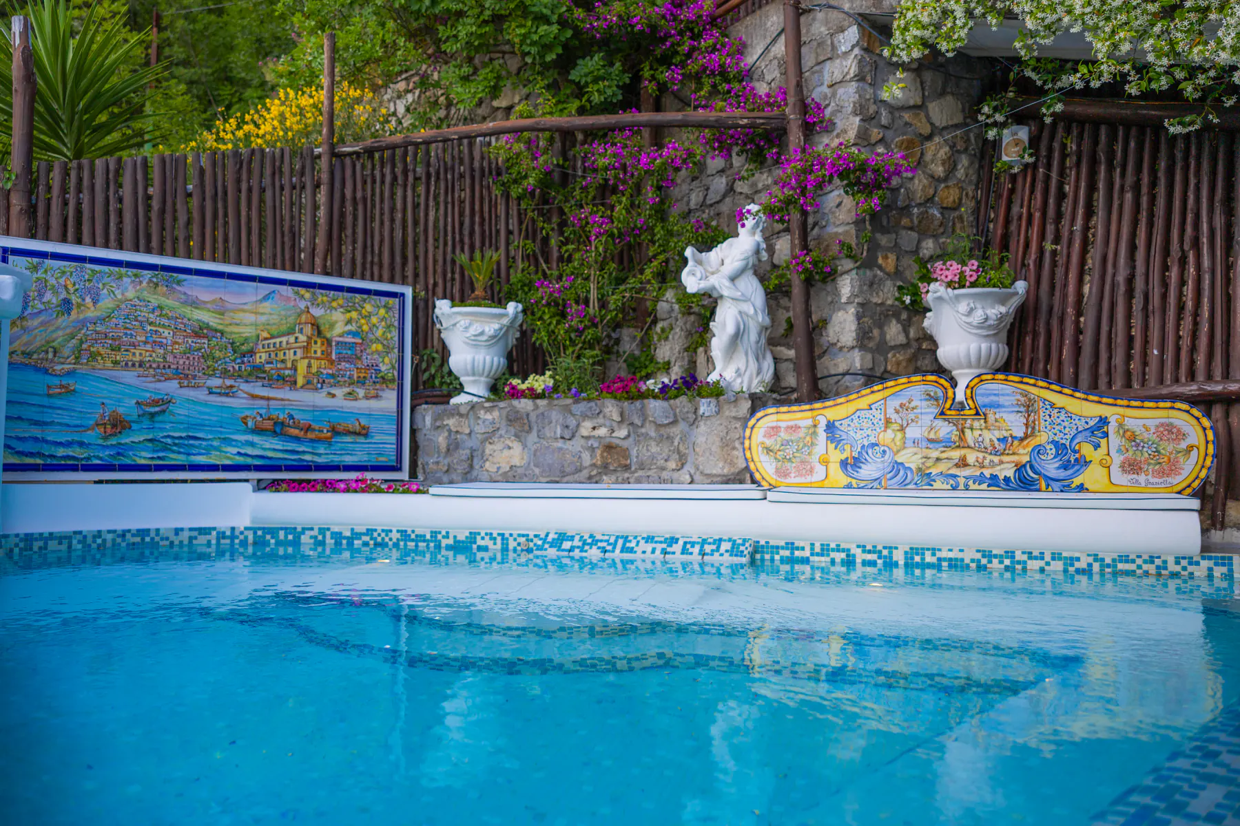 La piscina di Villa Graziella tra le maioliche e le statue del giardino