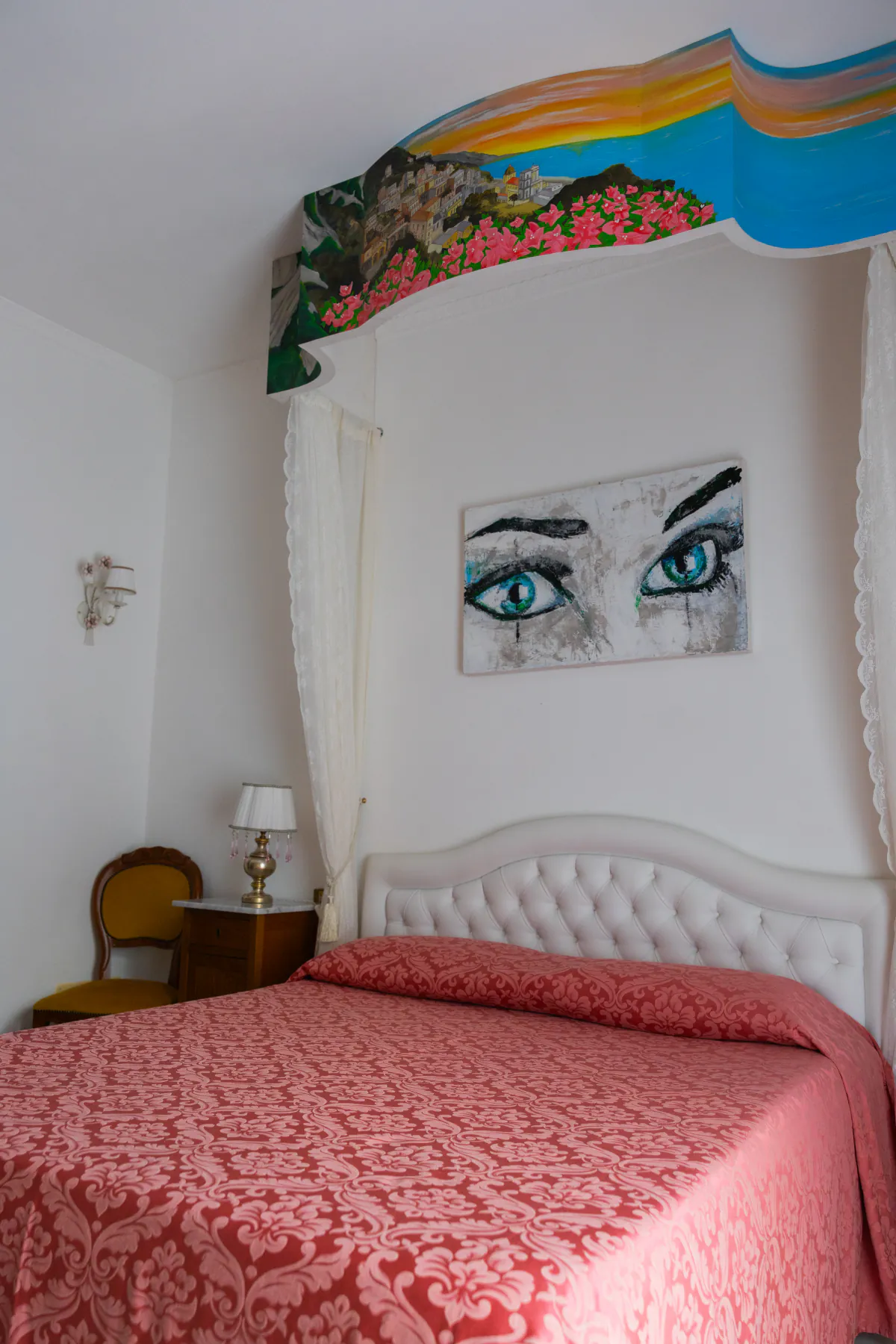 La camera corallo di Villa Graziella, con il murale della costa dipinto sopra il letto