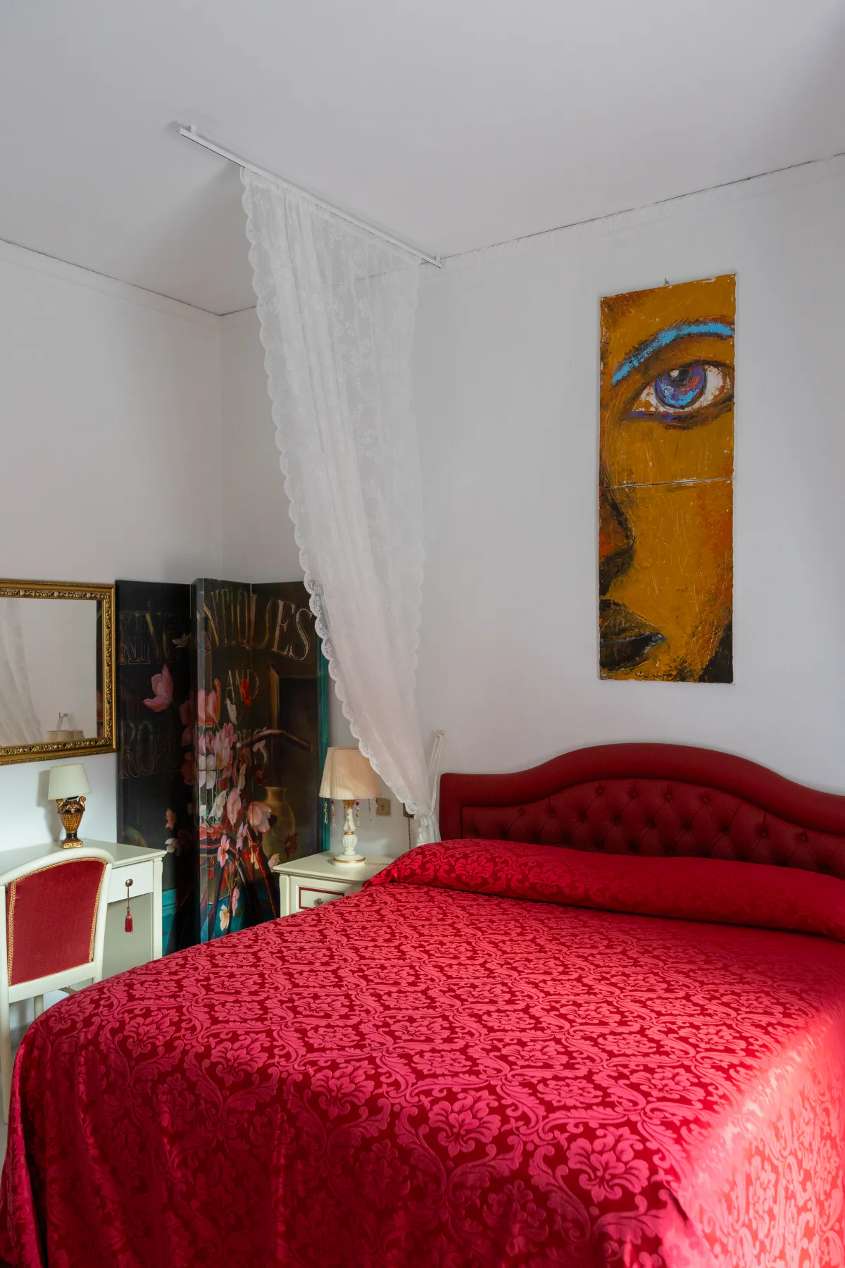 Il velo e il comò della camera rossa, con la tenda rossa alla finestra