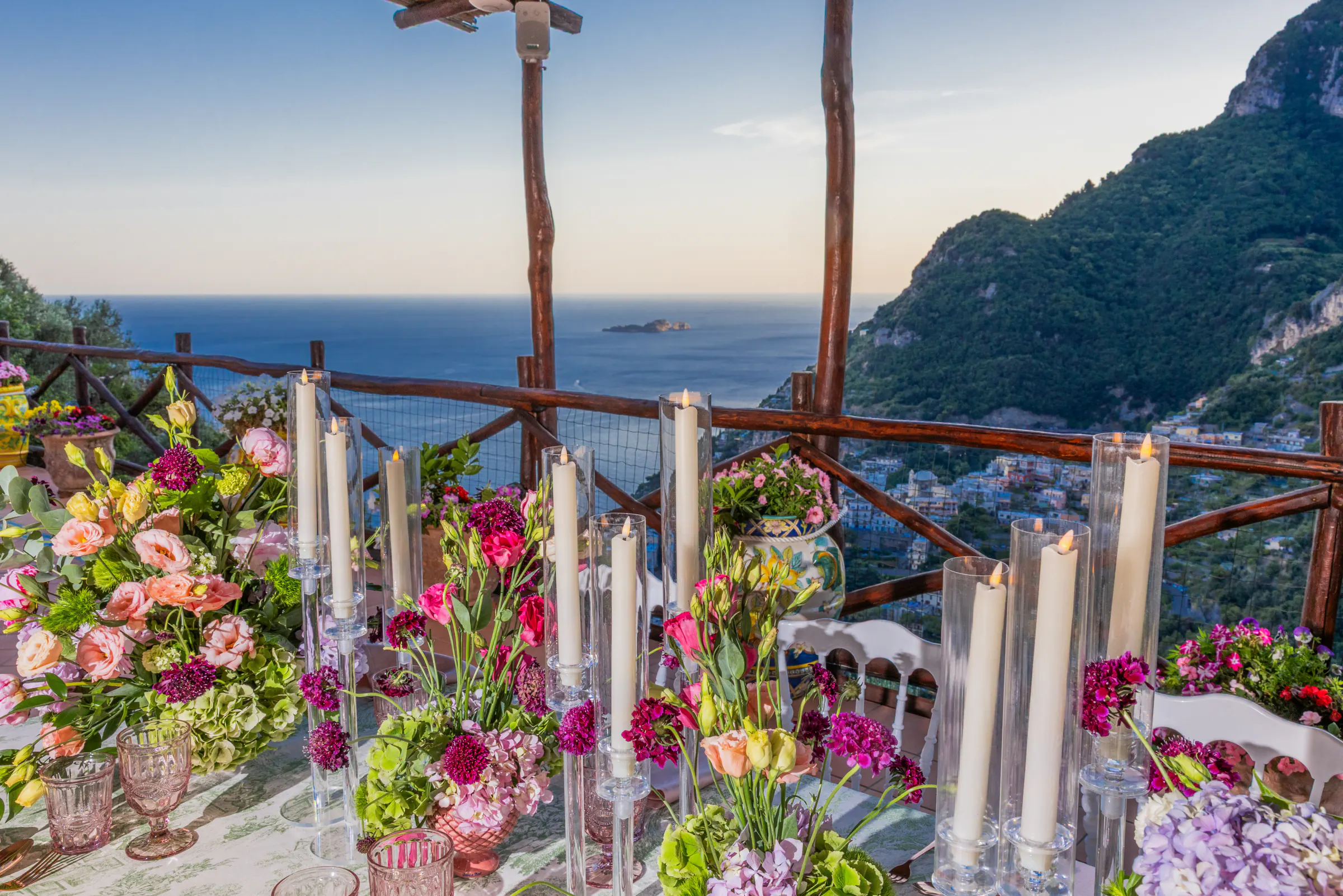 La tavola di un ricevimento sotto il pergolato della veranda, con il mare al tramonto alle spalle