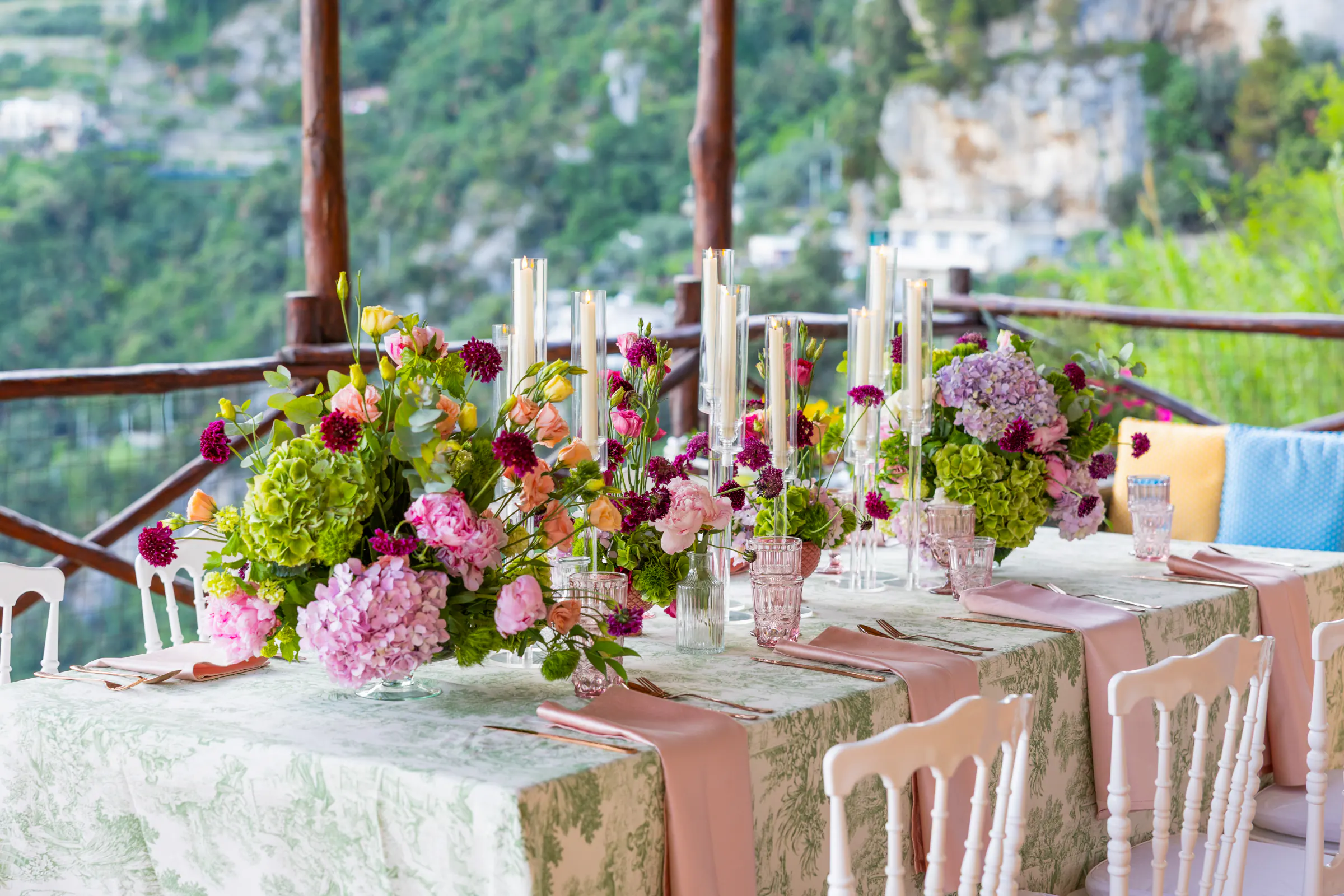La tavola lunga del ricevimento con i fiori, sotto il pergolato affacciato su Positano