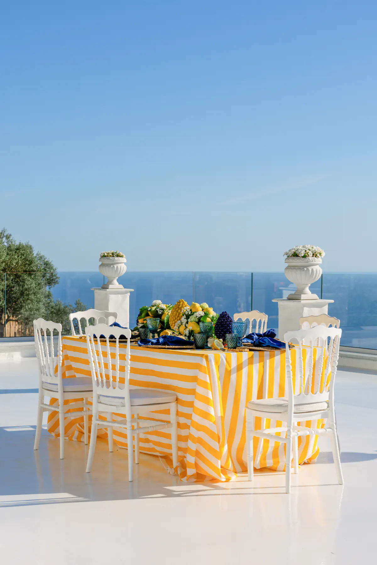 La tavola con la tovaglia a righe gialle e i limoni, sulla terrazza bianca affacciata sul mare